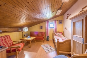 Une pièce chaleureuse avec un plafond en bois, un lit, un canapé, une table et une chaise.