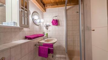 Un baño con ducha, lavabo y espejo.