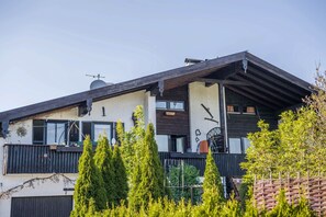 En toetages bygning med balkon, træbjælker og parabol.