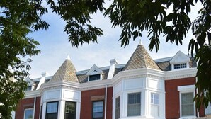 Una hilera de casas urbanas de ladrillo rojo con detalles blancos y ventanas salientes.