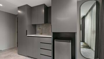 Una cocina moderna con armarios grises, un refrigerador de acero inoxidable y un espejo grande.