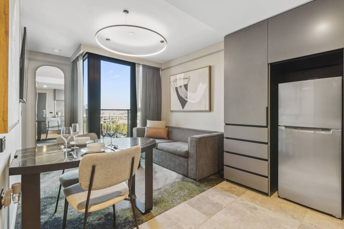 Una cocina moderna con comedor, sofá y un amplio ventanal con vistas a la ciudad.