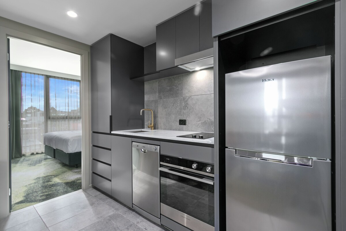 A modern kitchen with a stainless steel refrigerator, built-in oven, and dishwasher.