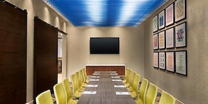 A conference room with a long table, yellow chairs, a large screen, and framed artwork on the walls. - Holiday Inn Express & Suites Kokomo South by IHG (Kokomo)