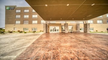 A Holiday Inn Express & Suites with a spacious entrance, a covered waiting area, and a brick facade.