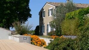 Un bâtiment moderne avec un toit en tuiles, entouré d’une végétation luxuriante et de fleurs orange.