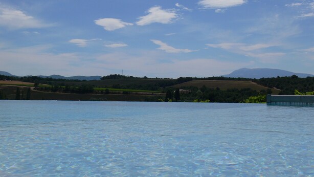 On aperçoit clairement une piscine, avec en arrière-plan un paysage lointain comprenant des champs et une chaîne de montagnes.
