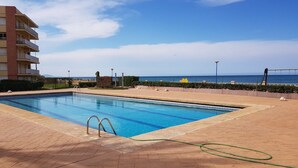 A swimming pool with a clear view of the ocean and a building in the background.