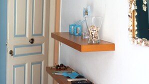 A room with a white door, a white sofa, and a wall-mounted shelf with decorative items. - Innaxos City Central Studio (Naxos)