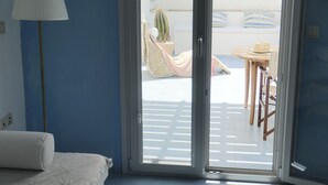 A room with a bed, a lamp, and a sliding glass door leading to an outdoor area with a table and chairs. - Innaxos City Central Studio (Naxos)