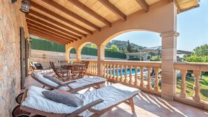 A covered outdoor seating area with lounge chairs and a view of a swimming pool. - Cosy Holiday Home "Solluna" with Wi-Fi, Pool, Terrace and Garden with Mountain View (Son Servera)