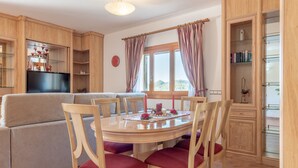A dining area with a round table, six wooden chairs with red cushions, a television, and a cabinet with glass shelves. - Cosy Holiday Home "Solluna" with Wi-Fi, Pool, Terrace and Garden with Mountain View (Son Servera)