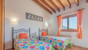 A bedroom with two beds, a window with curtains, a radiator, and a framed picture on the wall. - Cosy Holiday Home "Solluna" with Wi-Fi, Pool, Terrace and Garden with Mountain View (Son Servera)