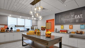 A modern kitchen with a central island, breakfast bar, and various food items displayed on the counter.