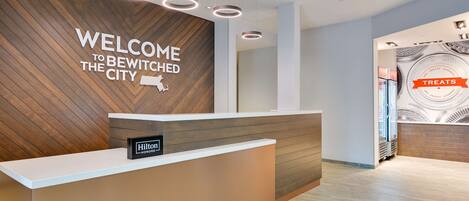 Un área de recepción de hotel moderna con una pared de madera y un letrero que dice "WELCOME TO BEWITCHED THE CITY".