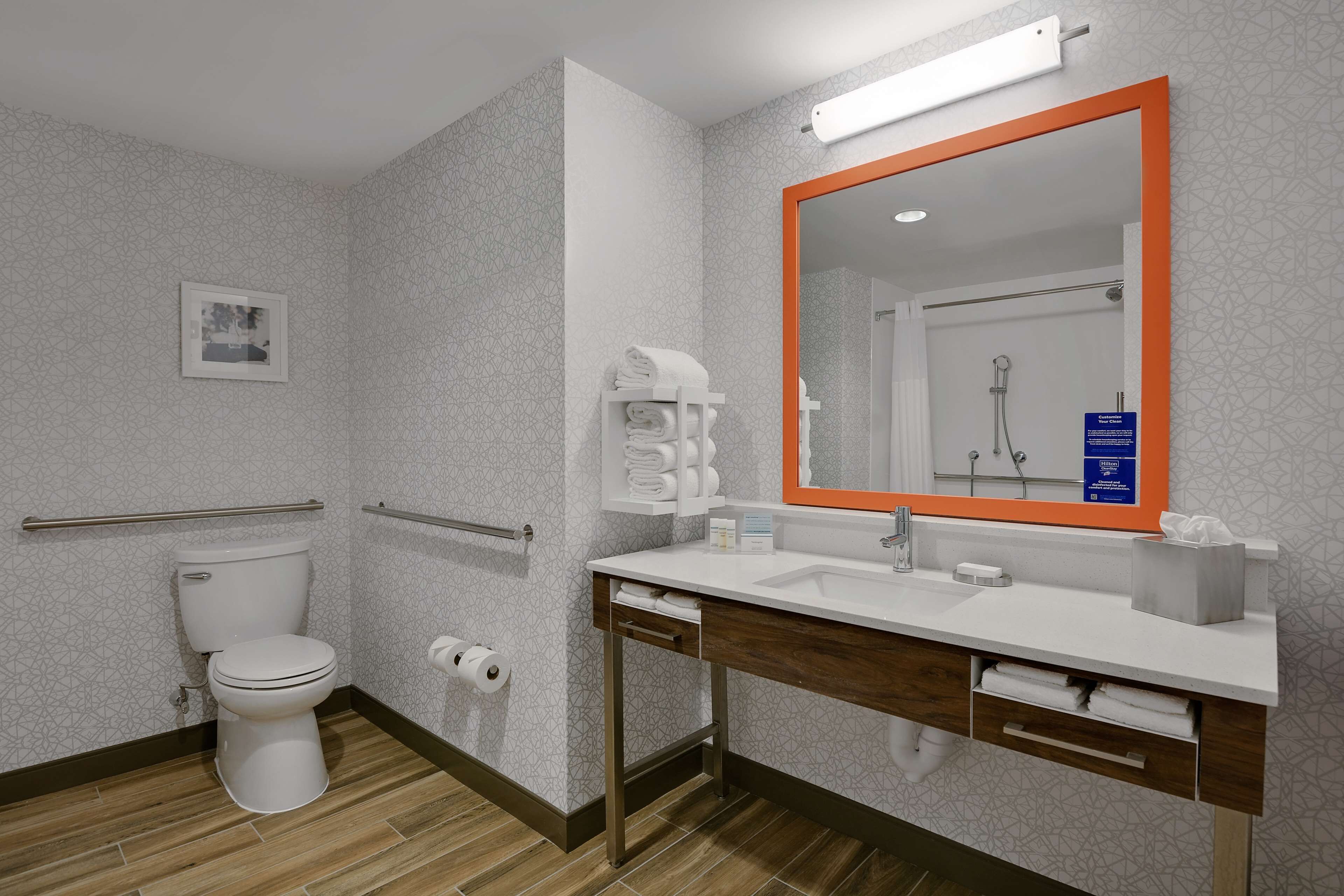 A modern bathroom with a toilet, sink, and mirror.