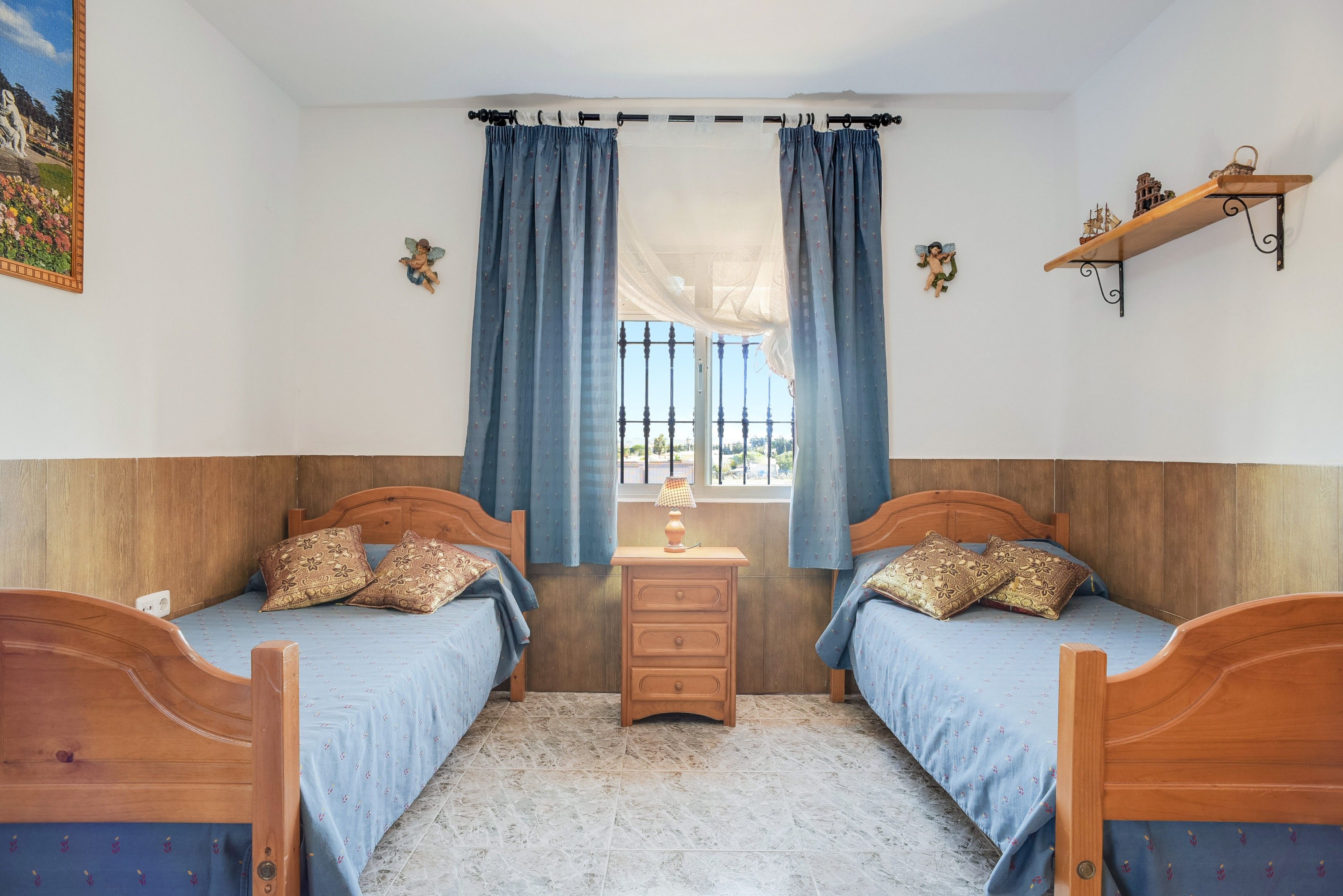 Een kamer met twee houten bedden, een nachtkastje en een raam met gordijnen.