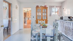 A dining area with a table set for two, a wooden cabinet, and a kitchen area with a microwave.