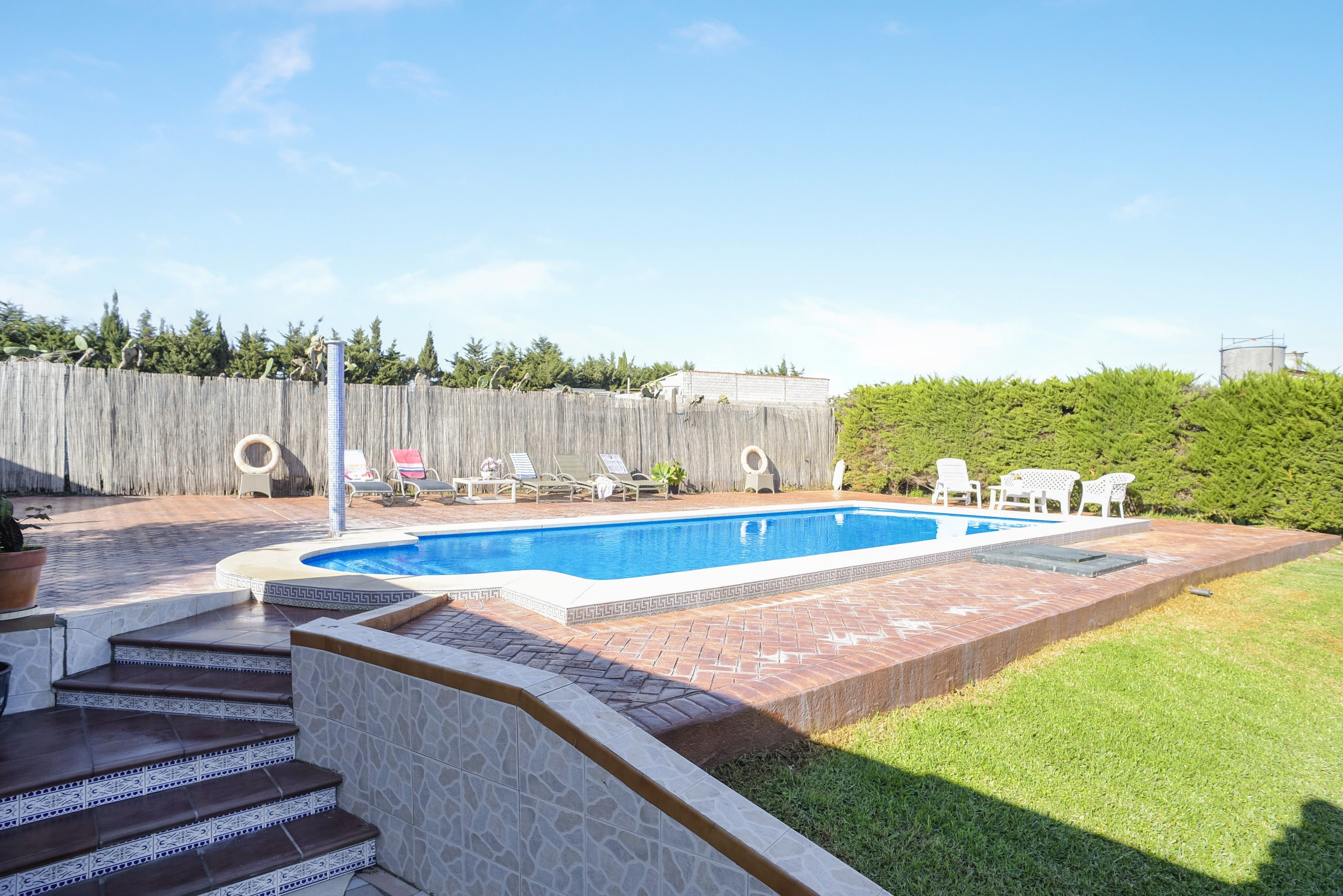 A backyard with a swimming pool, a wooden fence, and a grassy area.