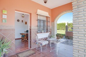 A patio area with a table and chairs, a hanging light fixture, and a view through an archway.