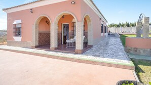 A two-story building with a pink facade, a tiled patio, and a stone pathway leading to the entrance.