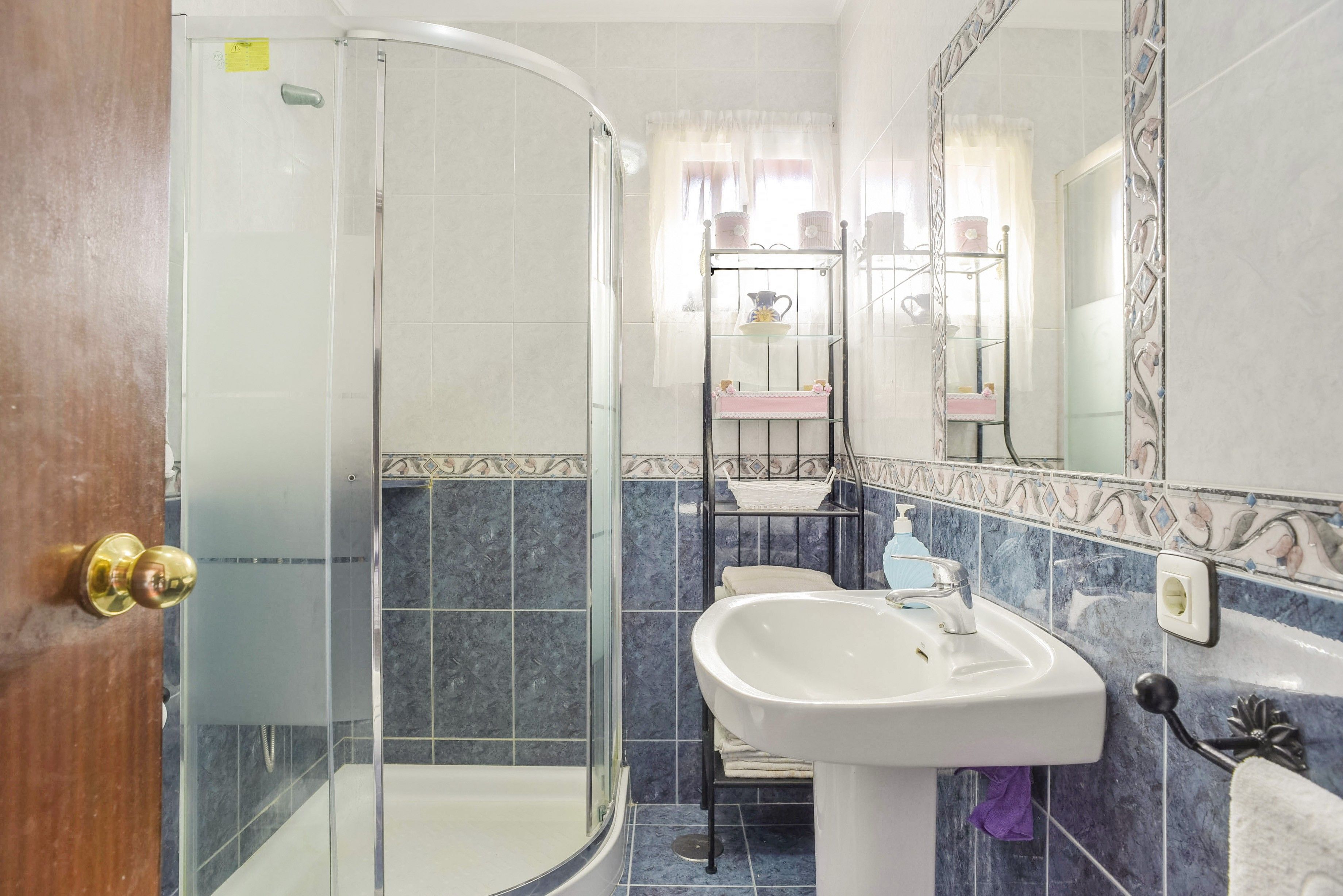 Un bagno con cabina doccia in vetro, un lavandino e un mobile vanitario con specchio.