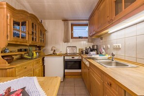 Une cuisine de taille réduite, dotée de meubles en bois, d’un réfrigérateur, d’un four, d’un évier et d’une fenêtre.
