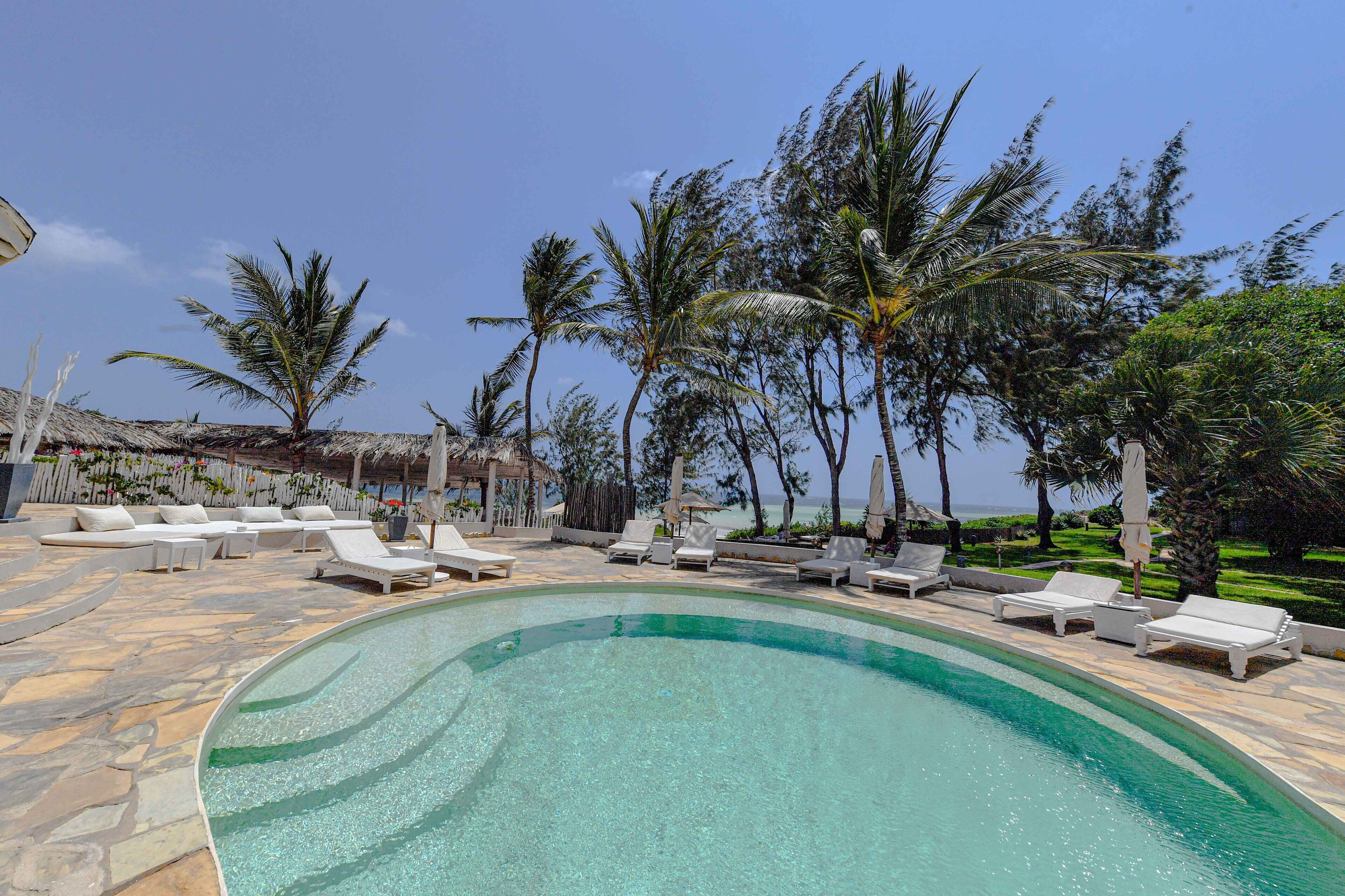 A pool area with lounge chairs and palm trees.