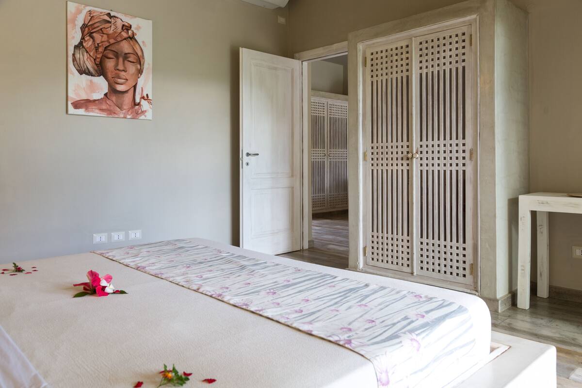 A bedroom with a bed, a bedside table, a wardrobe, and a painting on the wall.
