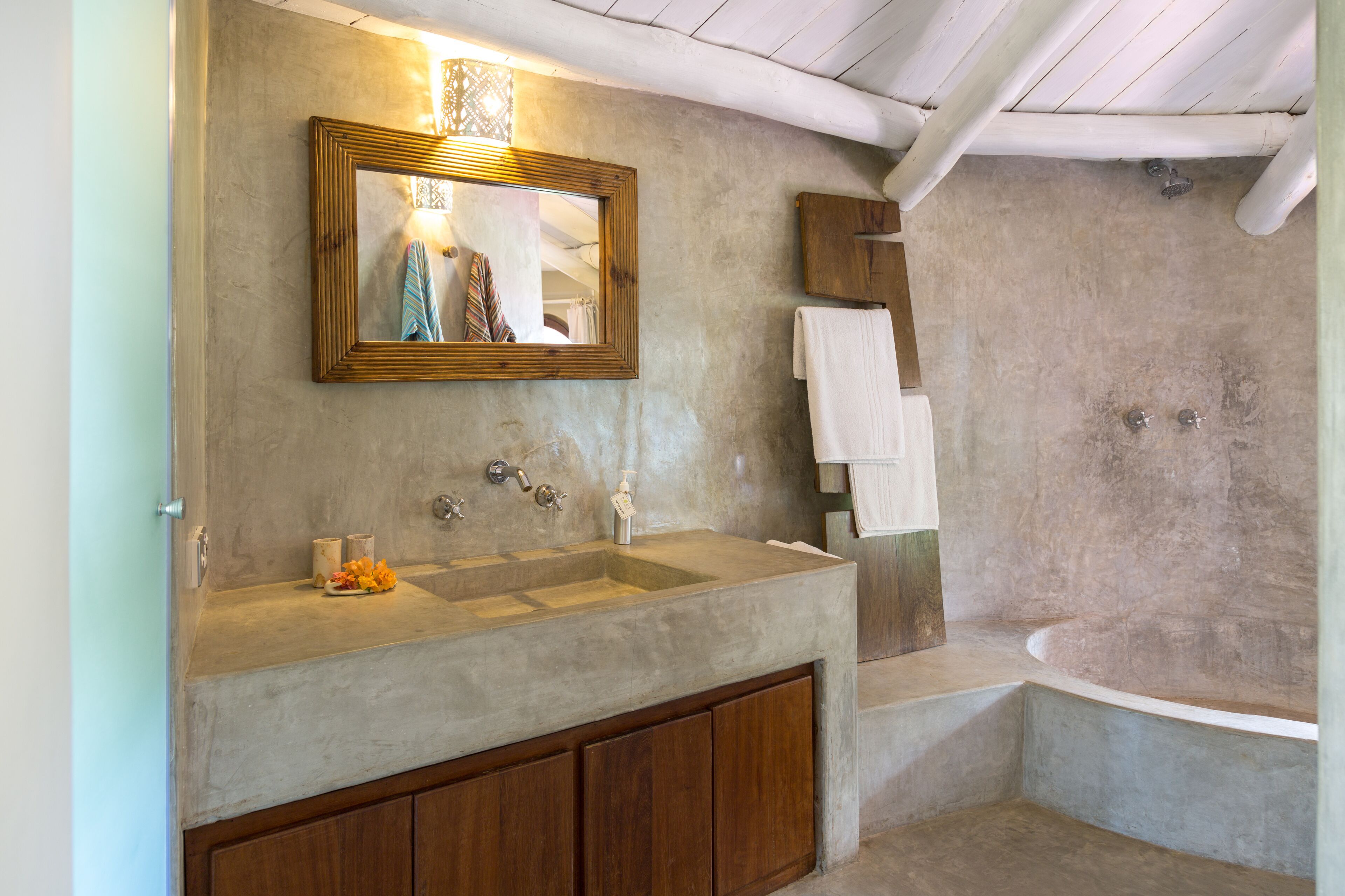 Un baño con lavamanos grande, espejo y ducha.