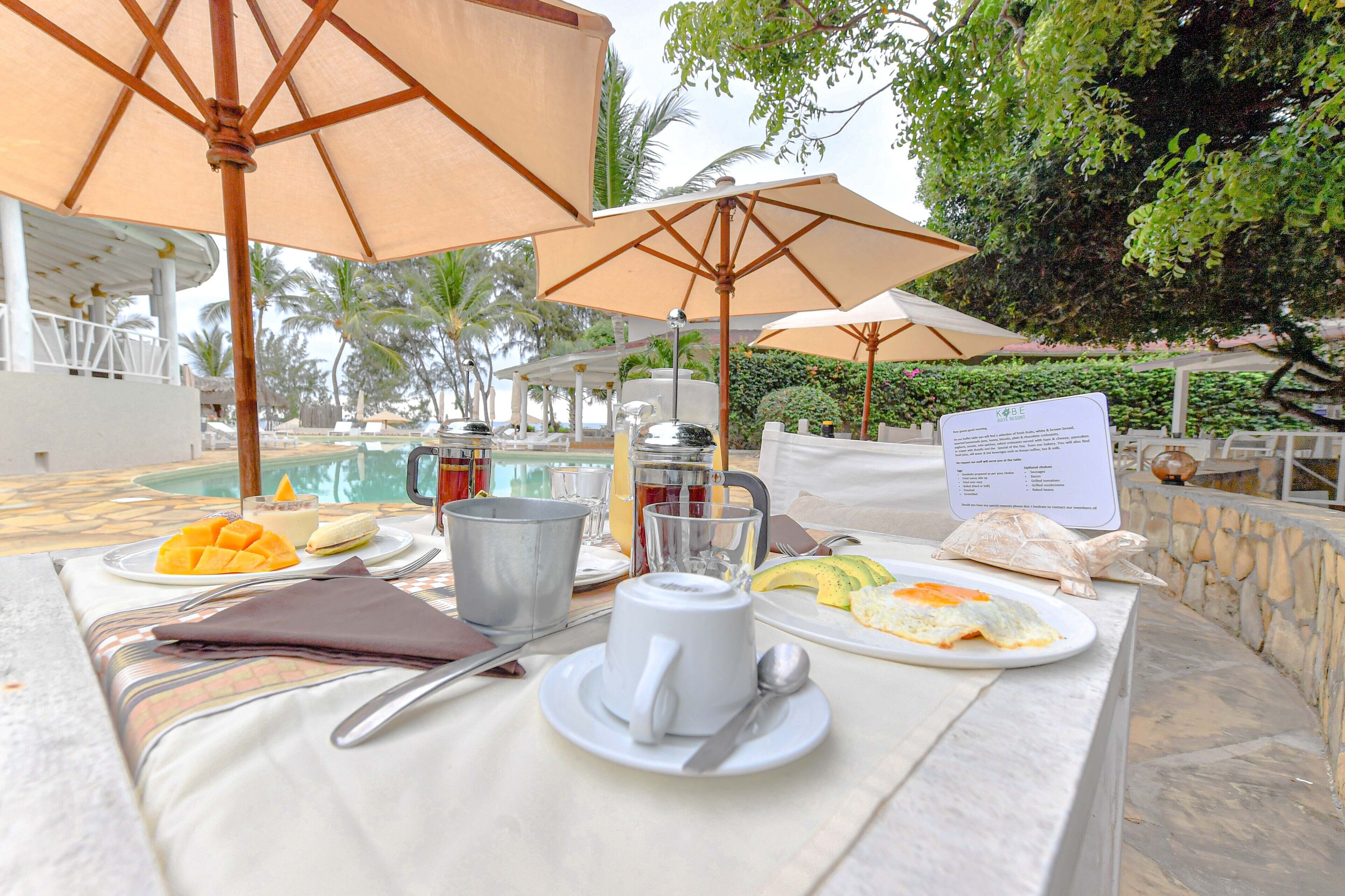 A table set for breakfast with a cup, plate of fruit, and a menu.