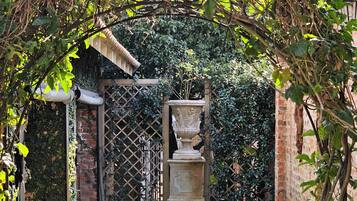 A garden pathway leading to a brick wall with a decorative urn.