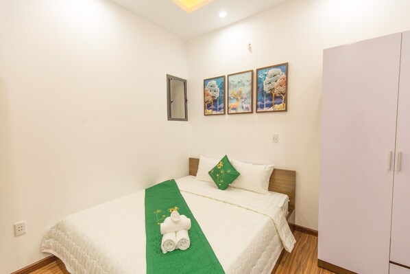 Una habitación de hotel con una cama, un armario y tres cuadros en la pared.