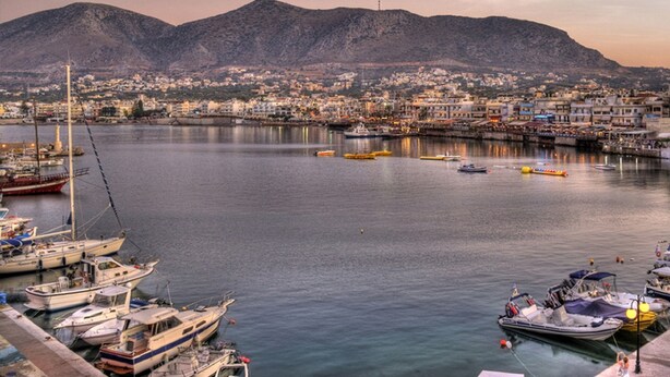 Un port avec des bateaux amarrés, une vue sur la ville en arrière-plan et une montagne.