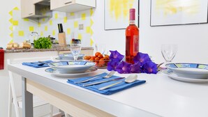 Een moderne keuken met een eettafel voor twee personen, compleet met borden, bestek en een fles rode wijn.