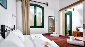 A hotel room with a bed, a window with curtains, a mirror, and a view of the outside. - Central Apt With Hydromasage Shower (Hersonissos)