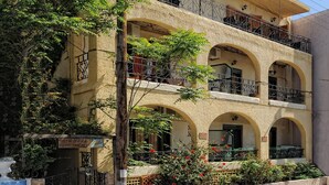 A multi-story building with balconies, arched windows, and a sign indicating it is an apartment complex. - Central Apt With Hydromasage Shower (Hersonissos)