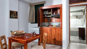 Uma cozinha compacta com armários de madeira, uma mesa de jantar com cadeiras e uma máquina de lavar pequena.