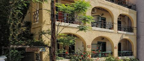 A multi-story building with balconies, arched windows, and a sign indicating it is an apartment complex.