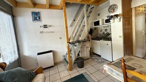 Uma sala de estar acolhedora com sofá, mesa de jantar e área de cozinha com escada.