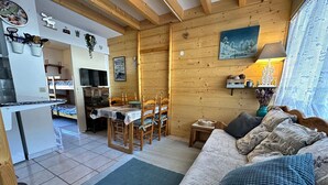 Interior acolhedor de uma cabana, com área de jantar, sofá com almofadas estampadas e cozinha.
