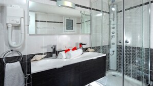A modern bathroom with a glass-enclosed shower, a white sink, and a black vanity.