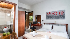 A hotel room with a bed, a desk with a laptop, a chair, a bathroom with a toilet, sink, and shower. - Charming Studio Near the Beach (Hersonissos)