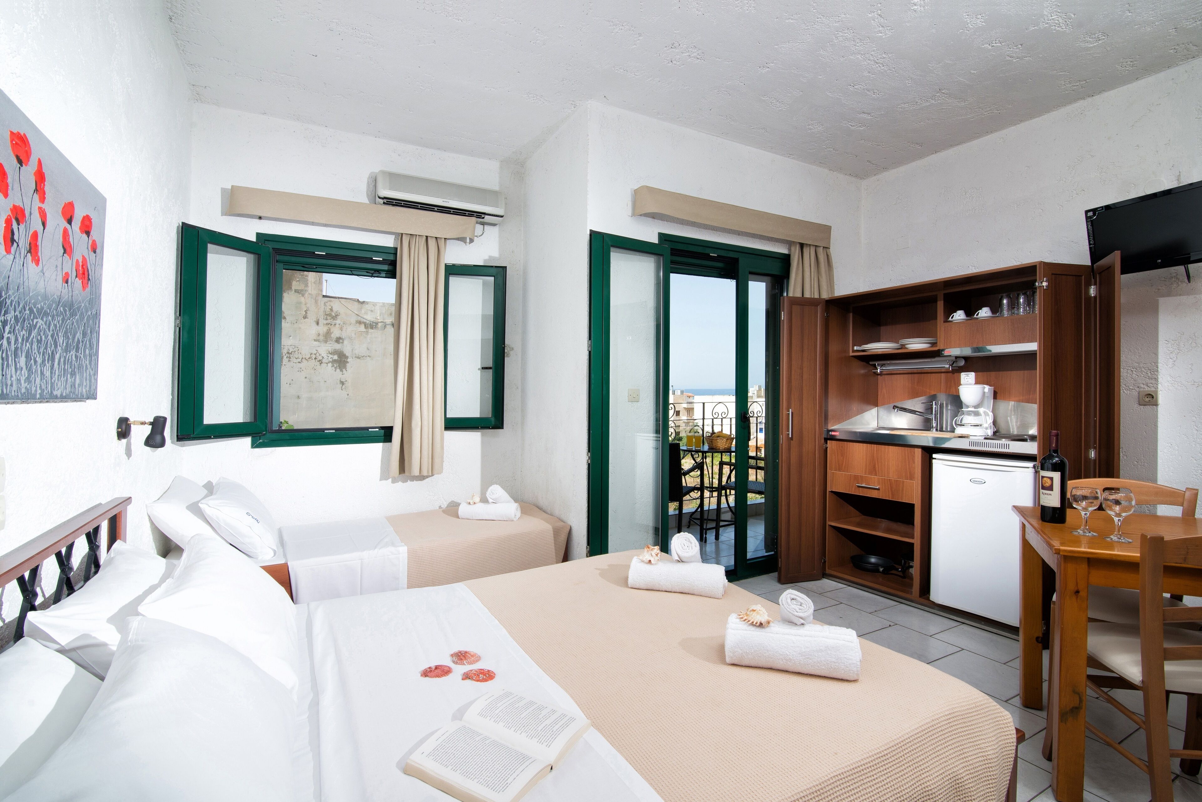 Une chambre d’hôtel avec deux lits, une kitchenette, un coin repas et une vue sur la ville.