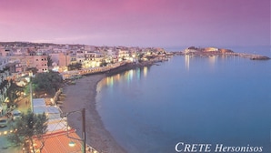 A coastal town at dusk with buildings along the waterfront and a clear view of the sea. - Charming Studio Near the Beach (Hersonissos)
