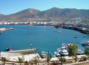 A coastal marina with boats docked, a lighthouse, and a town in the background.