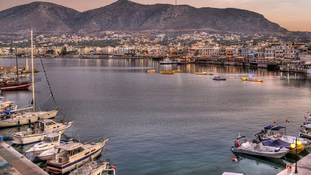 A harbor with boats docked, a cityscape in the background, and a mountain. - Charming Studio Near the Beach (Hersonissos)