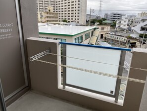 Un balcón con vista a un paisaje urbano, que incluye edificios y un estacionamiento.