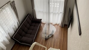 Ein modernes Zimmer mit einem dunkelbraunen Sofa, einem Glastisch und einem weißen Sessel.