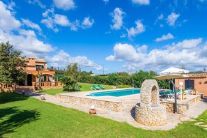 A pool area with a stone structure, a covered seating area, and a building with a tiled roof. - Rustic Holiday House Es Fasser with Pool, Garden, Terraces & Wi-Fi; Parking and Garage Available (Son Servera,)
